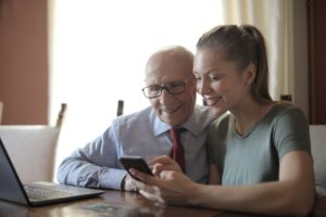 Junge Frau zeigt älteren Herrn etwas auf dem Smartphone